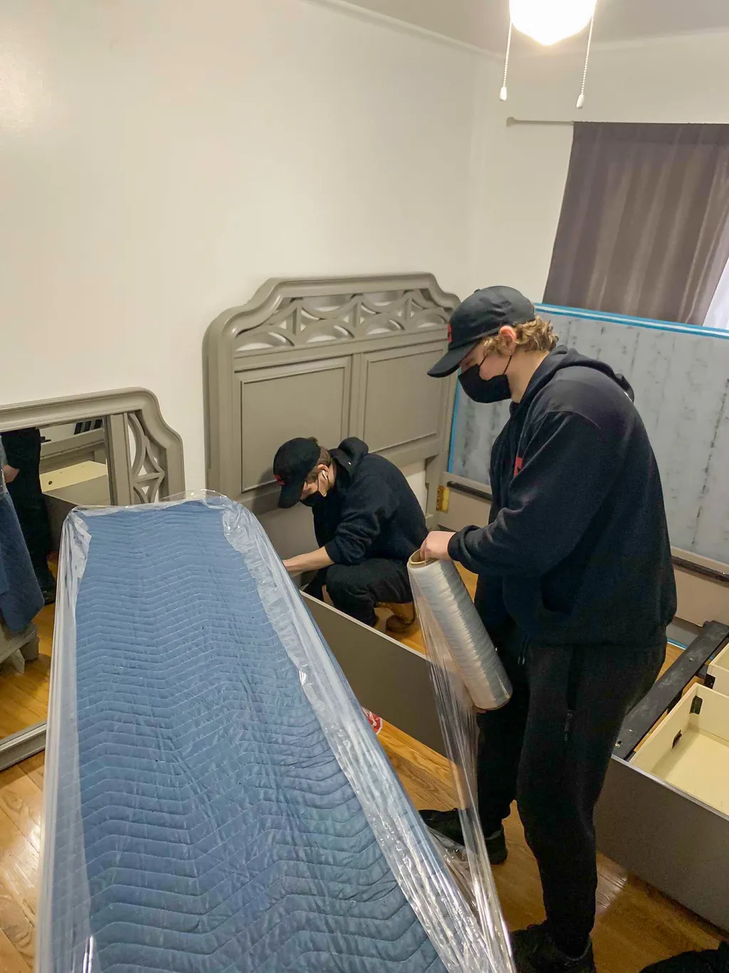 Two Monolith movers reassembling a bed frame in the new bedroom after a local downsizing move