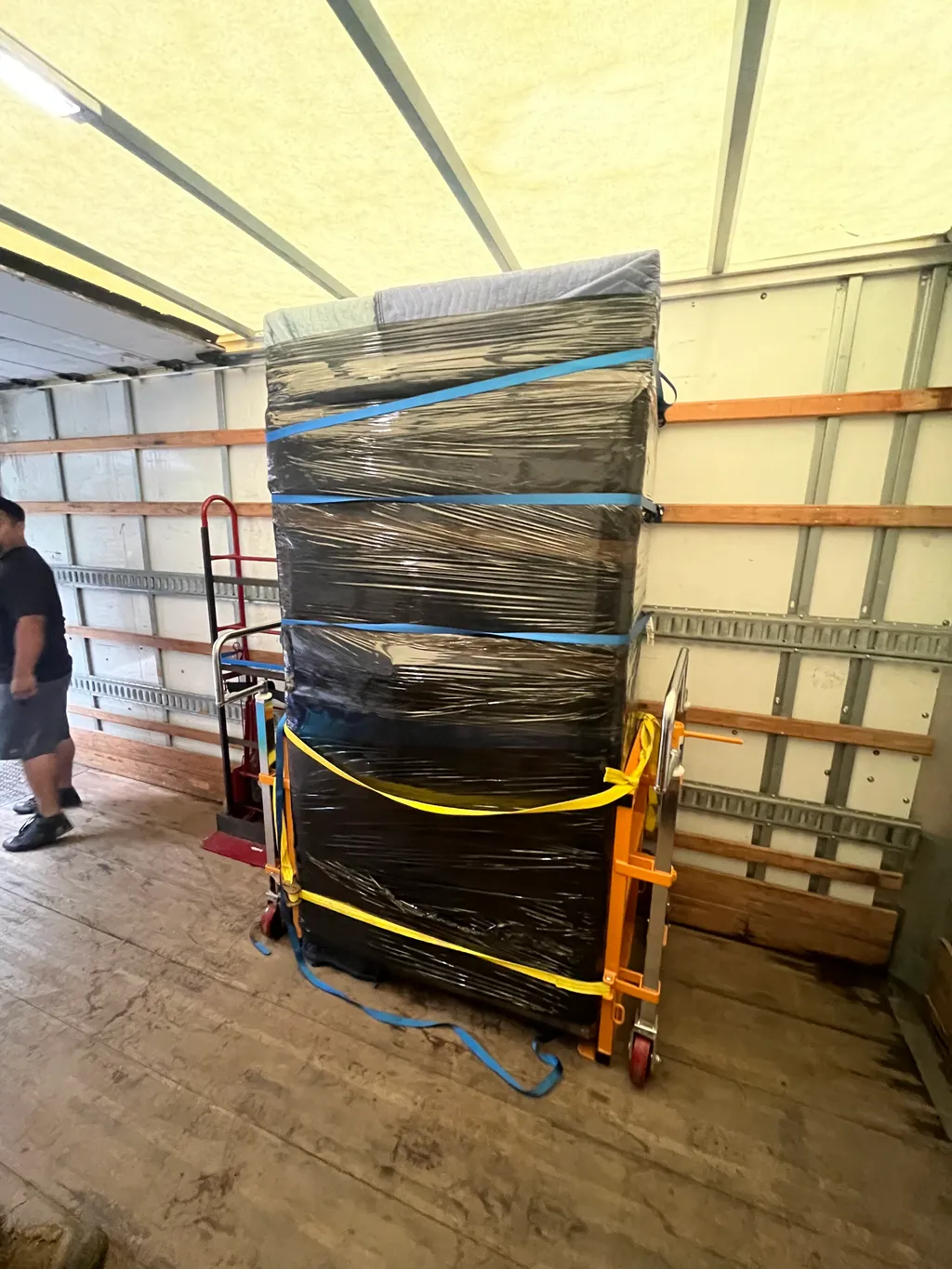 Wrapped and strapped office furniture secured on a dolly inside a Monolith Moving Company truck